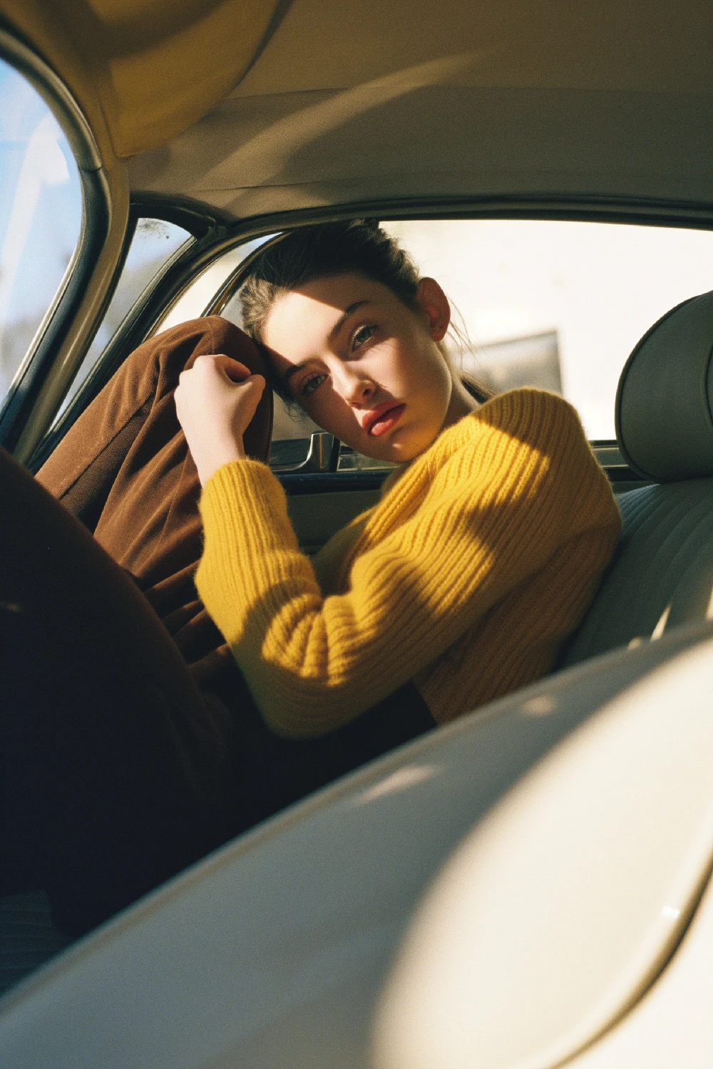 A woman sitting in the back seat of a car, looking out the window with a serene expression.